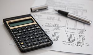 A calculator on top of a paper with a lot of numbers.