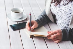 A woman writing down something on a small notebook